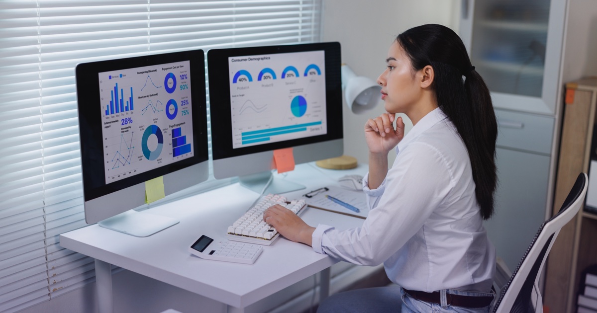 A professional reviews information on two computer monitors.